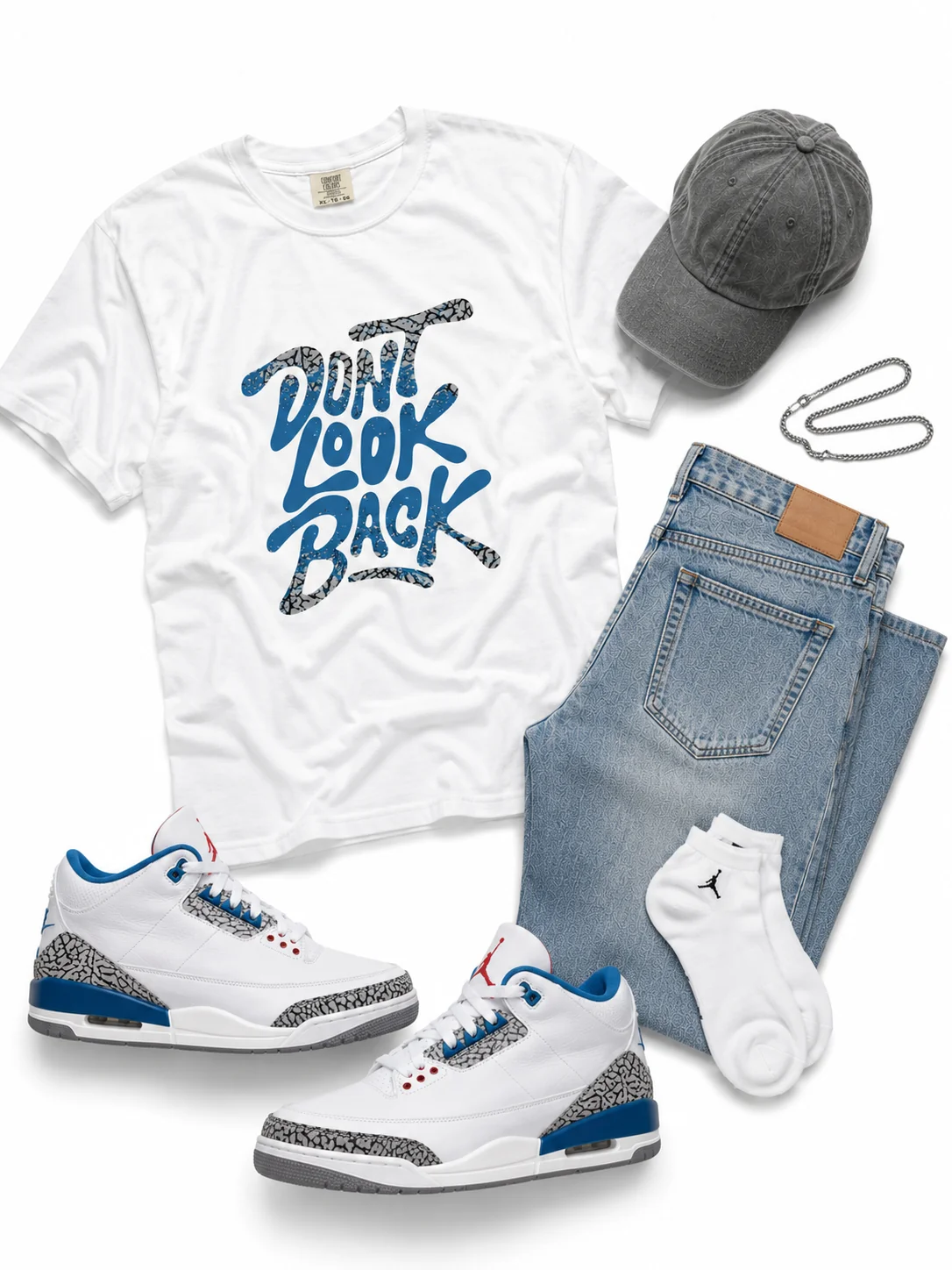 Blue Letter Day flat-lay - white heavyweight graphic tee with bold graffiti lettering in true blue and cement grey elephant-print texture, reading don't look back paired with the Air Jordan 3 OG 'True Blue' - 2026